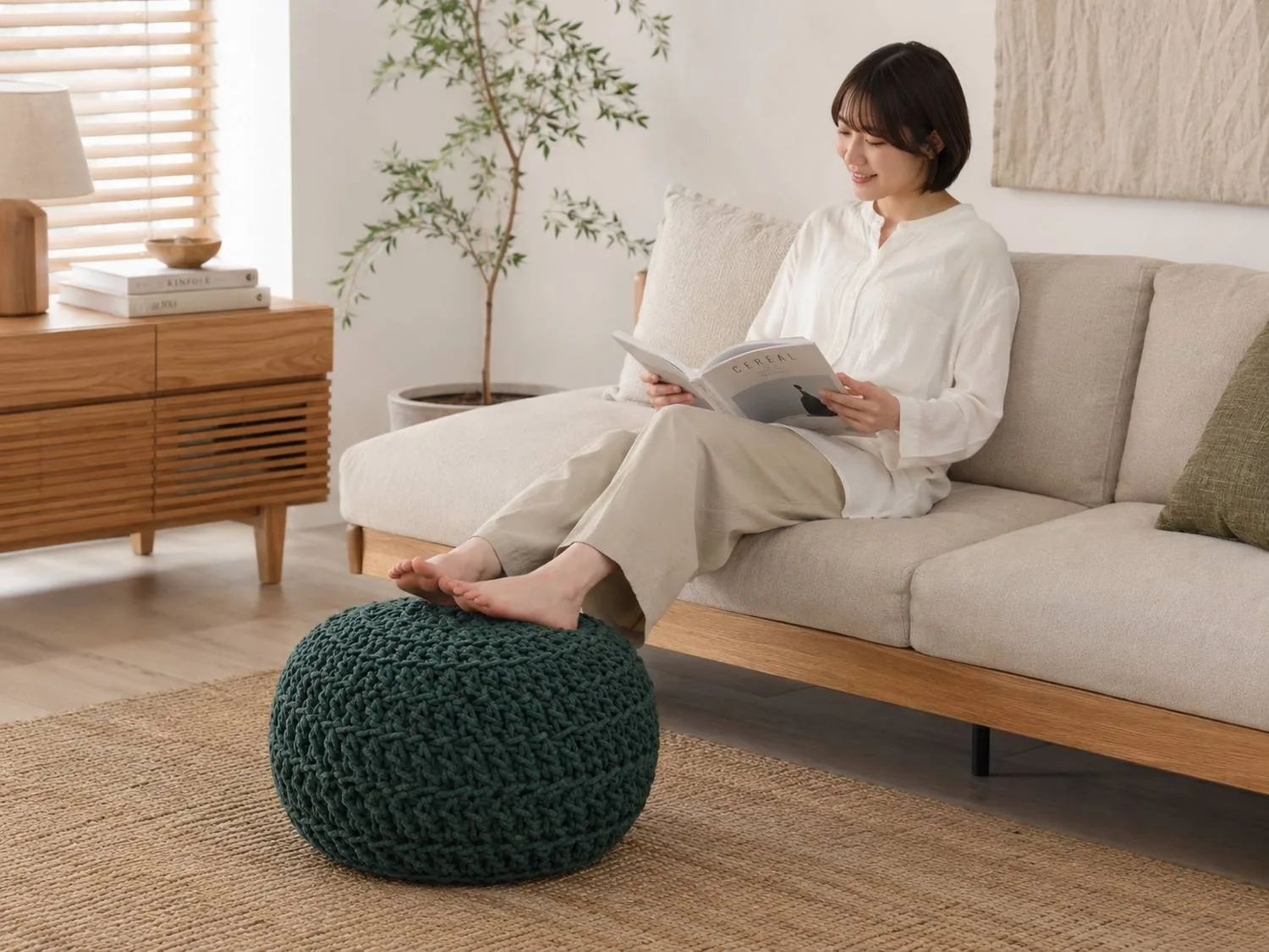 プフ01のソファでくつろぎながらプフに足を置くオットマンの使用例。色・サイズは掲載商品と異なる場合があります。